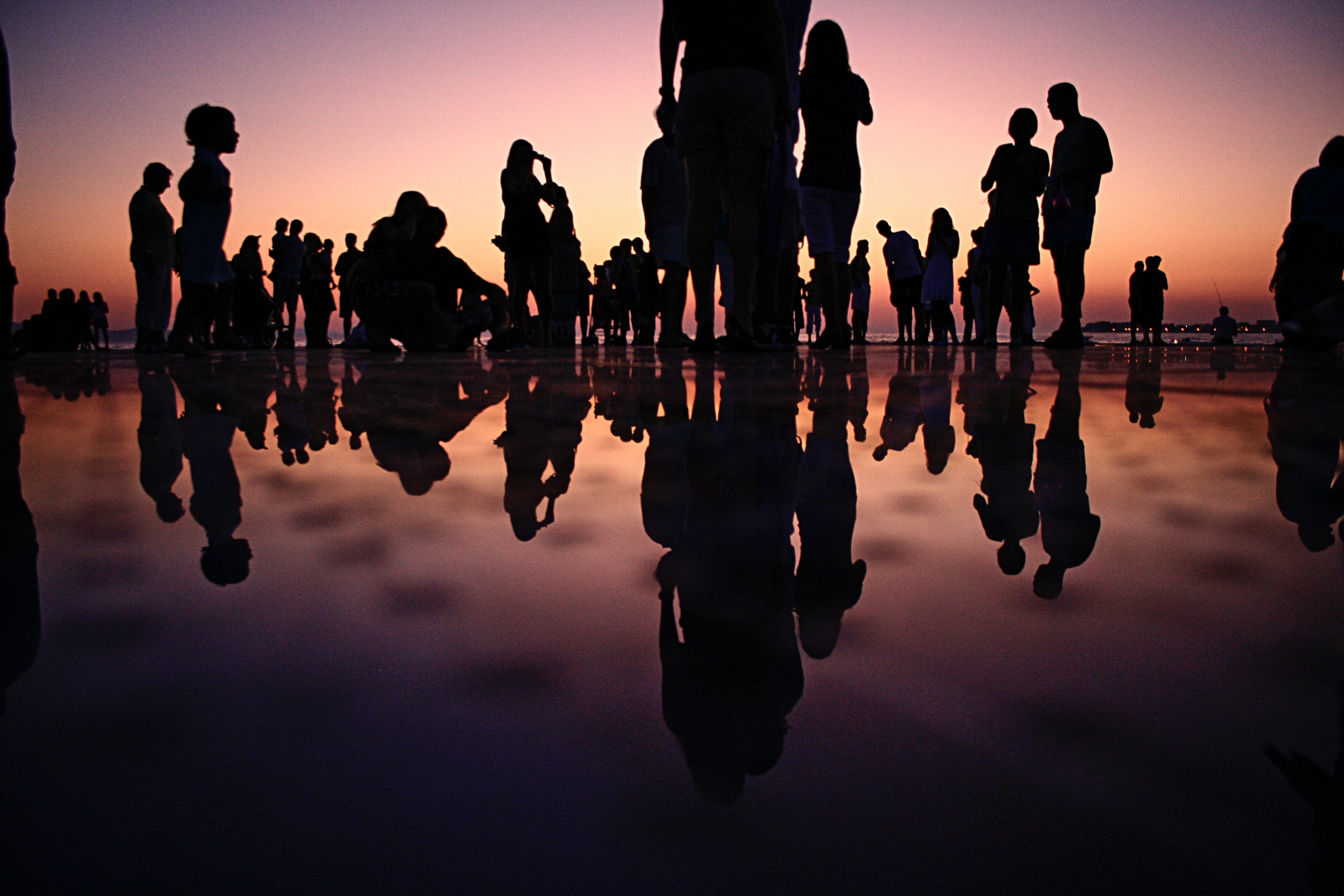 A crowd at a party with water showing their reflection in silhouette