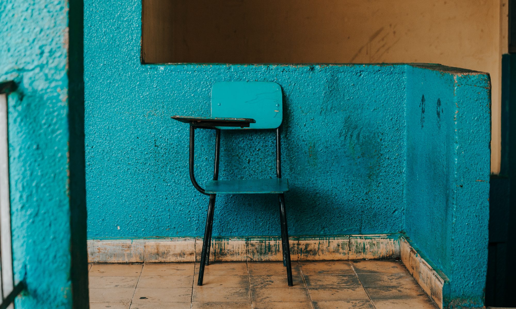 Old style school desk painted blue against a blue wall.